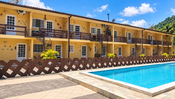 Un hotel con piscina, varios balcones y un cielo azul despejado.