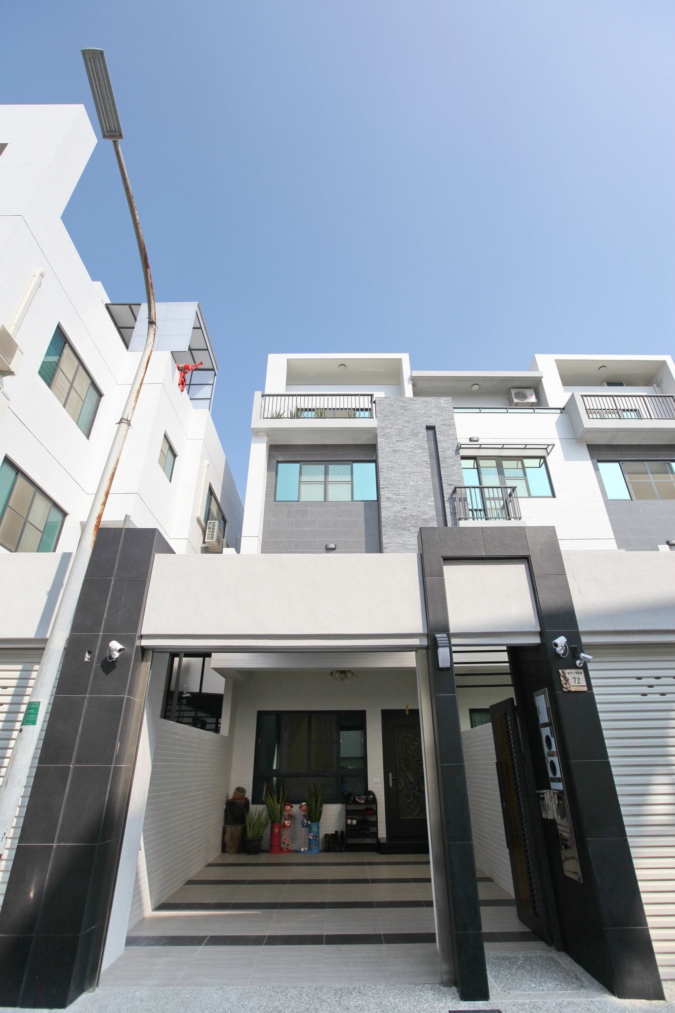 Un edificio residencial moderno de varios pisos con una entrada destacada, ventanas amplias y techo plano.