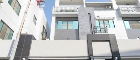 Um edifício residencial moderno de vários andares, com entrada destacada, grandes janelas e telhado plano.