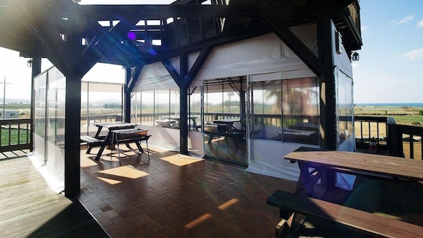 Eine Außenterrasse mit Tisch und Stühlen, ein überdachter Sitzbereich und eine Aussicht auf die Landschaft.