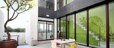Um edifício moderno com uma varanda, uma mesa de jantar e cadeiras.