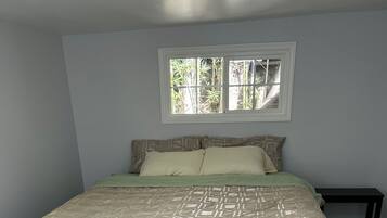 Un dormitorio con cama, mesita de noche y ventana.