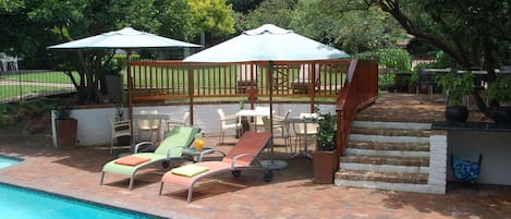 A poolside area with lounge chairs, a covered seating area, and a brick staircase.