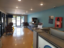 Zona de recepción con mostrador, asientos, máquina de café y extintor.