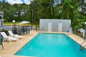 A swimming pool with lounge chairs and a small building with doors. - Days Inn by Wyndham Hardeeville Near Hilton Head (Hardeeville)
