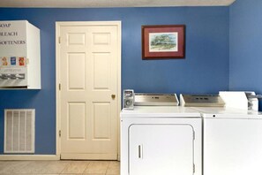 A laundry area with a white door, a framed picture on the wall, and a washing machine. - Days Inn by Wyndham Hardeeville Near Hilton Head (Hardeeville)