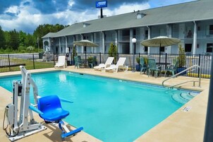 Un hotel con piscina, sillas de descanso y sombrillas.