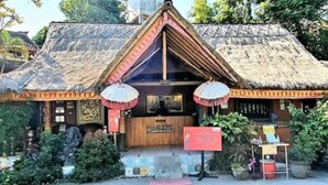 A traditional thatched-roof building with a wooden front desk, surrounded by greenery.