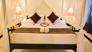 A bed with a canopy, pillows, a heart-shaped decoration, and towels.
