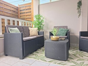 A patio area with wicker furniture, including a sofa and chairs, a small table with a plant, and a decorative basket. - Zaboka 3★ – appartement calme et spacieux avec terrasse privative (Petit-Bourg)