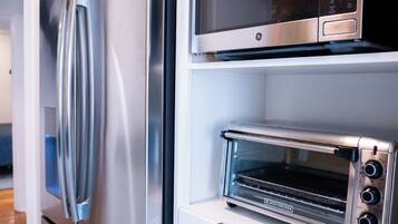 A modern kitchen with a stainless steel refrigerator, a microwave, and a built-in toaster oven.