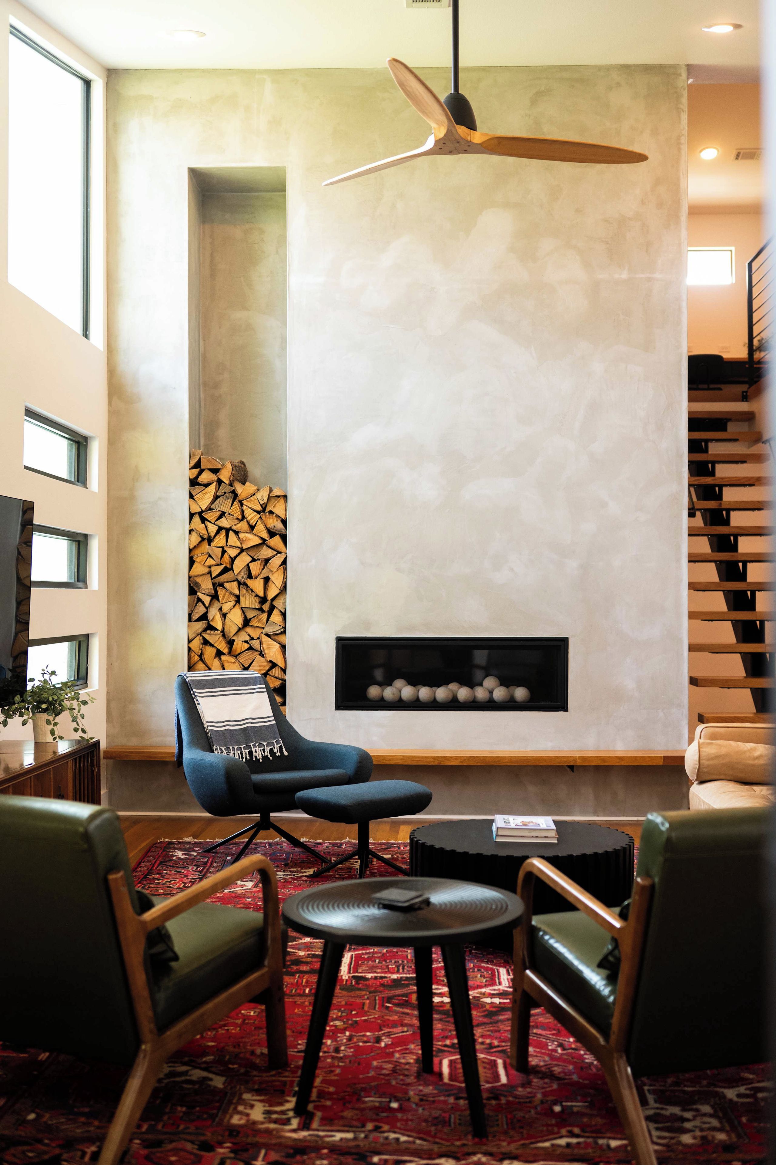 Una sala de estar moderna con chimenea, un sillón azul, una mesa de centro y una alfombra estampada.