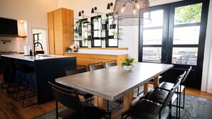 Una cocina moderna con una isla central, sillas negras y una lámpara colgante.