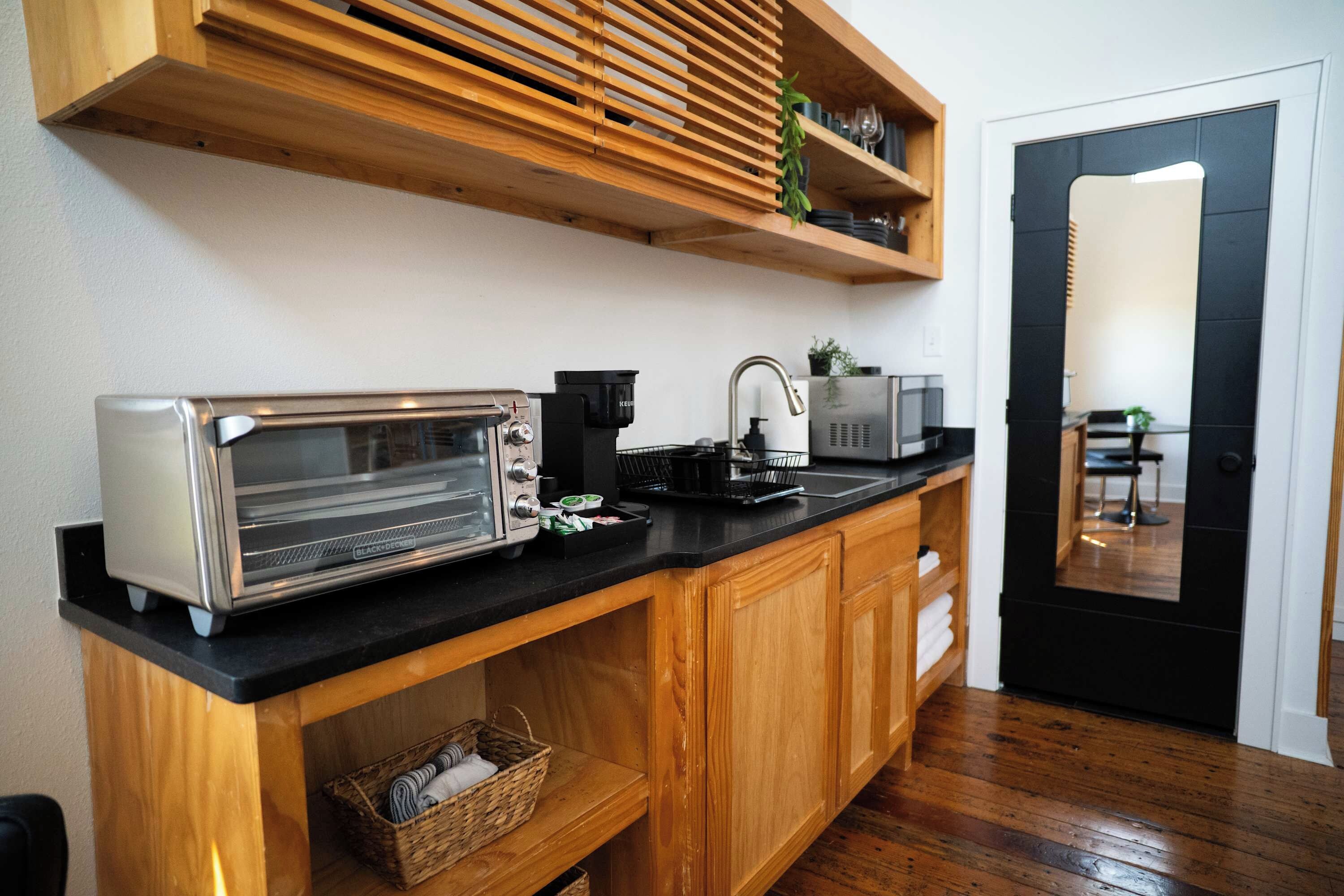 A compact kitchen with a toaster, microwave, and a coffee maker on the counter.