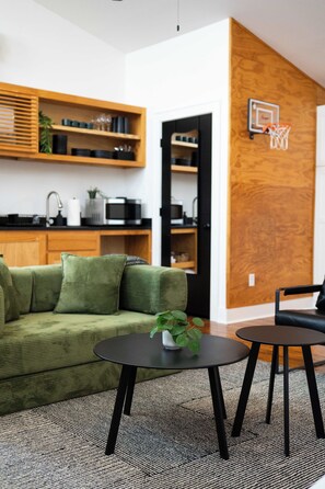 En moderne stue med en grøn sofa, et lille rundt bord med en plante og en sort stol.