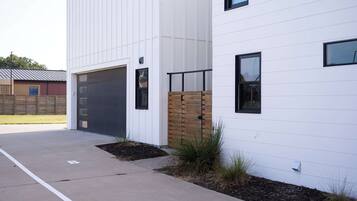 Un bâtiment moderne doté d’une porte de garage, d’une clôture en bois et d’une allée pavée.
