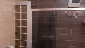 Un baño con inodoro, cabina de ducha y una toalla en el suelo.