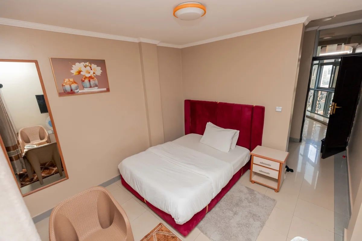A bedroom with a bed, a nightstand, a chair, a mirror, and a painting on the wall.