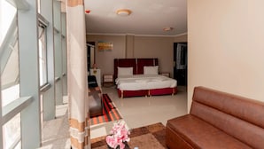 A hotel room with a bed, a sofa, a desk, and a window. - Gihozo Hotel (Kigali)