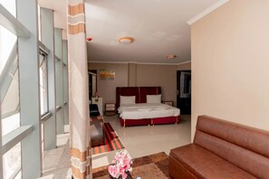 A hotel room with a bed, a sofa, a desk, and a window. - Gihozo Hotel (Kigali)
