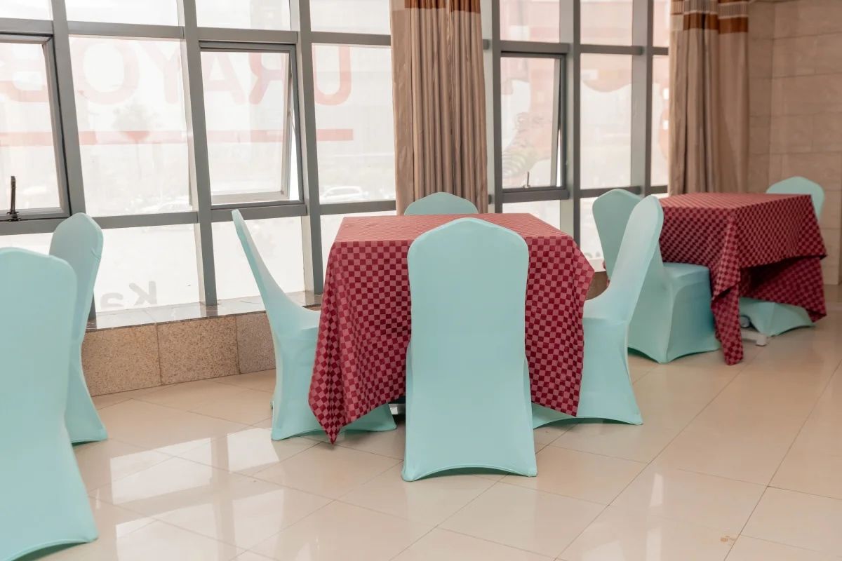 A dining area with tables and chairs, large windows, and curtains.