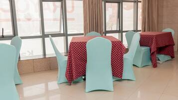 A dining area with tables and chairs, large windows, and curtains.