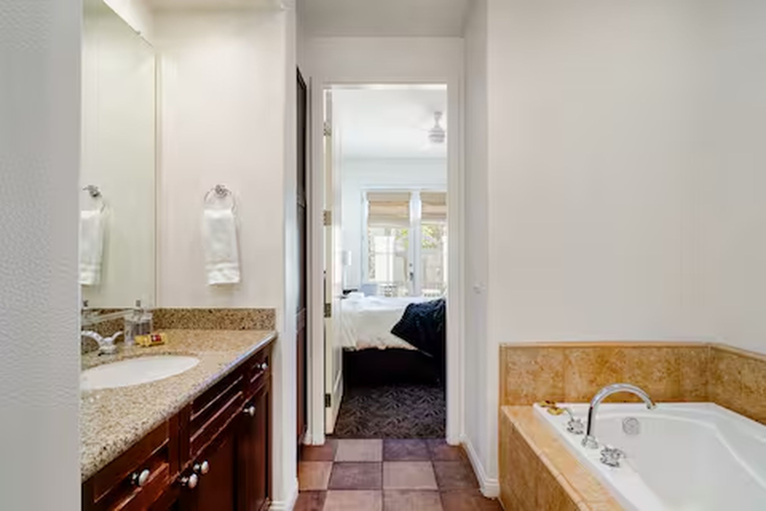 A bathroom with a sink, mirror, and bathtub.