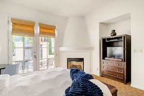 A bedroom with a bed, a dresser, a fireplace, and a balcony. - Legacy Villas Studio En-suite with Fireplace,Patio, Pools, Kitchenette, Grnd Flr (La Quinta)