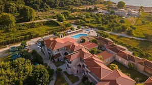 A coastal resort with terracotta-roofed buildings, a swimming pool, and lush greenery. - Elina Hotel Perdika (Igoumenitsa)