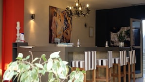 A modern kitchen with a bar area, a chandelier, and a large abstract painting on the wall. - Elina Hotel Perdika (Igoumenitsa)