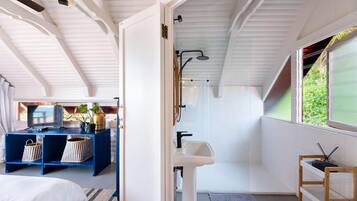 Un baño moderno con ducha, lavabo y vistas a la vegetación.