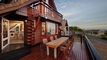 Una cabaña de madera con terraza, comedor y vistas del paisaje circundante.