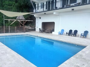 A swimming pool with a clear blue water surface, surrounded by a white building with a balcony and outdoor seating. - Mountain Oasis-Farm Stay solar powered with swimming pool. Quiet and peaceful. (San German)