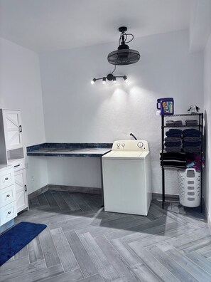 A laundry room with a washing machine, a drying rack, and a ceiling fan. - Mountain Oasis-Farm Stay solar powered with swimming pool. Quiet and peaceful. (San German)