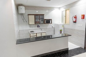 A modern kitchen with a marble countertop, built-in microwave, and a refrigerator. - Noor Amal Hotel Apartments As Sulay (Riyadh)