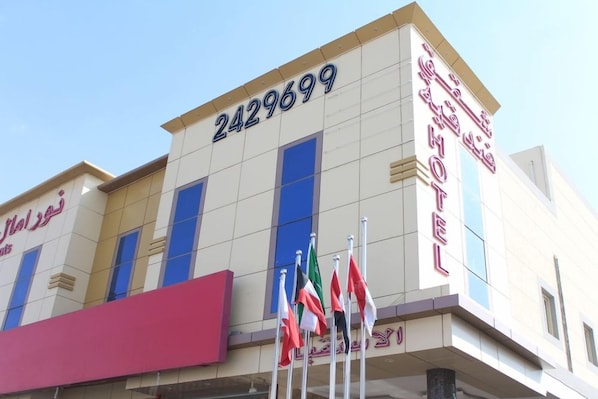 A hotel building with a large number '2429699' on the facade, flags in front, and Arabic text indicating it's a hotel. - Noor Amal Hotel Apartments As Sulay (Riyadh)