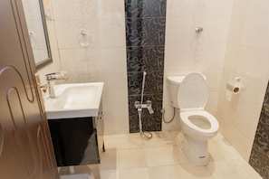 A bathroom with a white sink, a toilet, and a shower. - Noor Amal Hotel Apartments As Sulay (Riyadh)