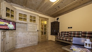 Een woonkamer met een televisie, bank en open haard.
