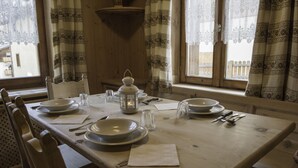 Een eettafel gedekt met borden, bestek en een kaars.