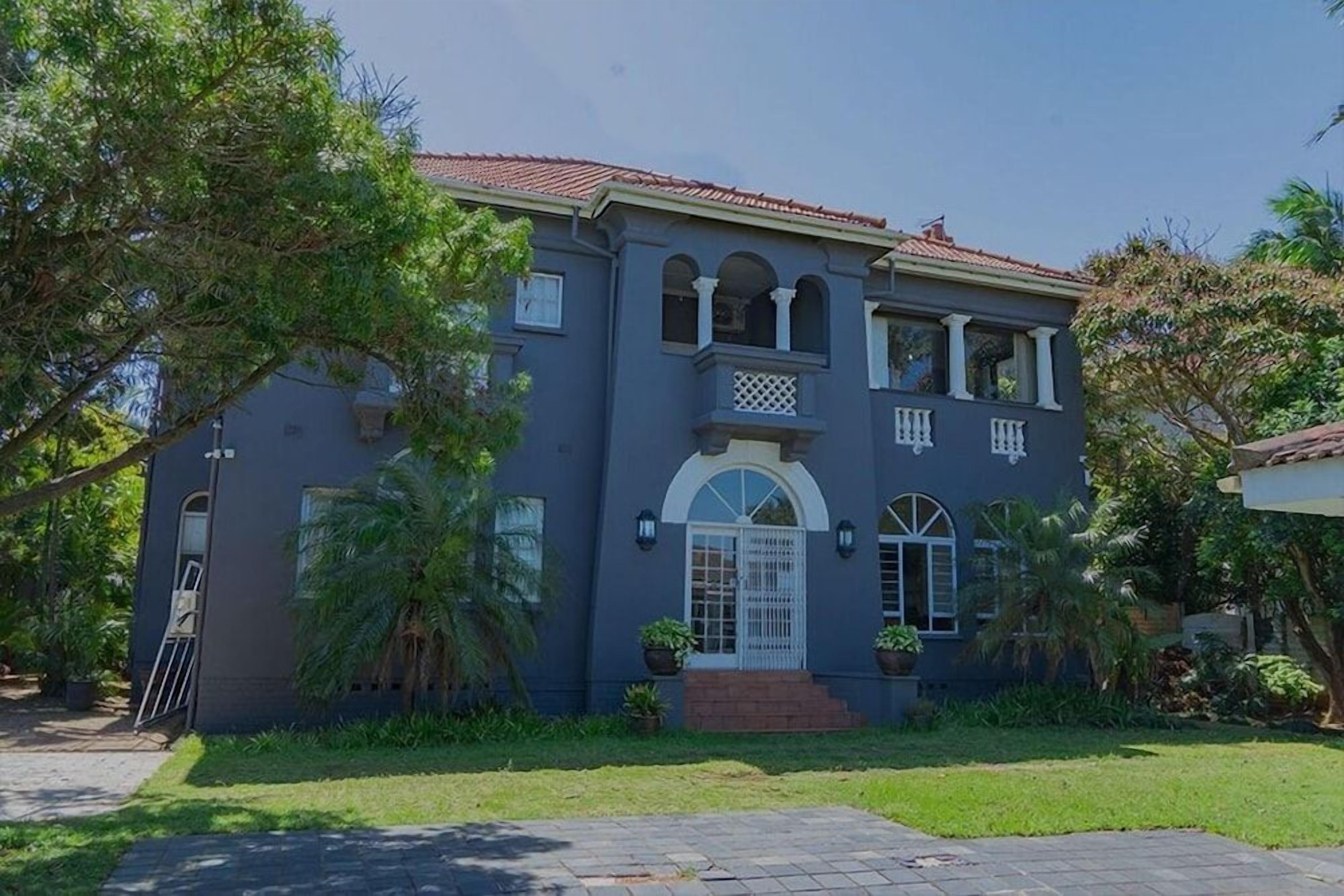 A two-story house with a front entrance, a balcony, and a tiled roof.
