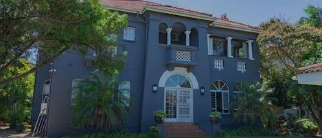 A two-story house with a front entrance, a balcony, and a tiled roof.