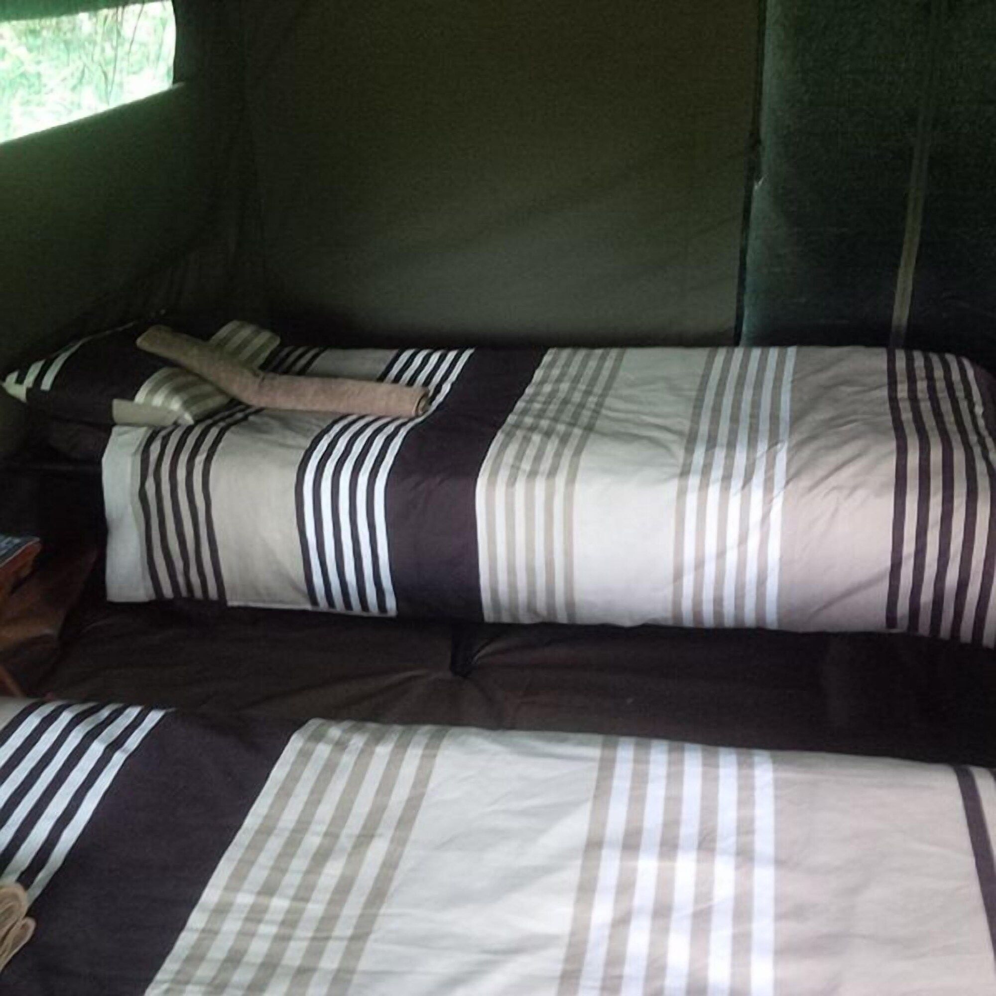 Ein Zimmer mit zwei Betten, jeweils mit gestreifter Bettwäsche.