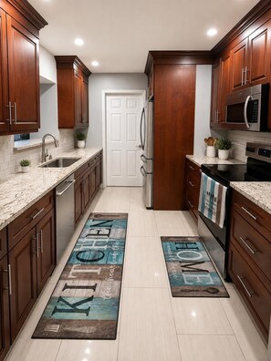 A modern kitchen with wooden cabinets, stainless steel appliances, and a kitchen island. - Casa Palma - A South Florida Oasis (Deerfield Beach)