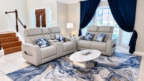 A living room with a beige sofa set, a coffee table, and a patterned rug.