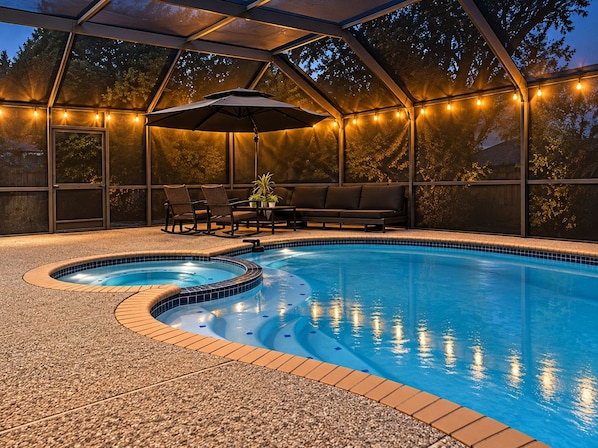 Ein Swimmingpool mit Whirlpool, umgeben von einer überdachten Terrasse mit Sitzgelegenheiten und Lichterketten.