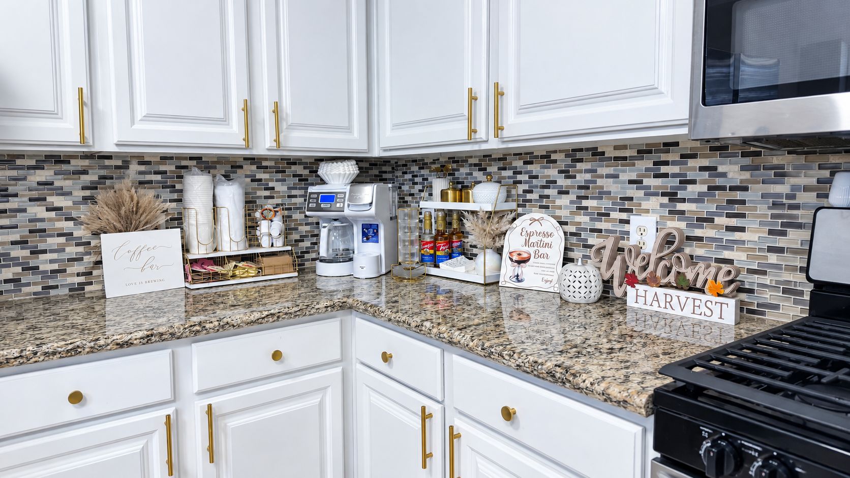 A kitchen with white cabinets, a granite countertop, and a coffee station.