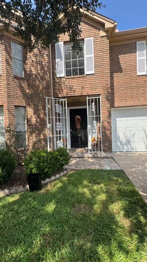 A two-story brick house with a front entrance, a garage, and a well-maintained lawn.
