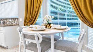 A dining area with a round table, white chairs, and a vase with white flowers.
