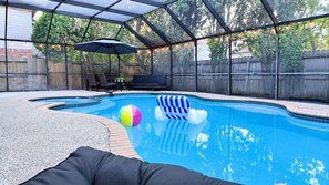 Ein Pool mit überdachtem Bereich, Liegestühlen und einem Strandball.