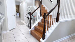 A staircase with wooden steps and white railings, leading to an upper floor.